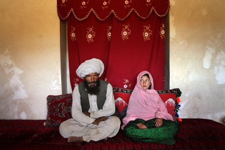 Portrait of soon to be wed Faiz Mohammed, 40, and Ghulam Haider, 11, at her home in a rural village of Damarda in Ghor province. Ghulam said she is sad to be getting engaged as she wanted to be a teacher. Her favorite class was Dari, the local language, before she was made to drop out of school. Married girls are seldom found in school, limiting their economic and social opportunities. Parents sometimes remove their daughters from school to protect them from the possibility of sexual activity outside of wedlock. It is hard to say exactly how many young marriages take place, but according to the Afghan women's ministry and women's NGOs, approximately 57 percent of Afghan girls get married before the legal age of 16. In addition, once the girl's father has agreed to the engagement, she is pulled out of school immediately. Early pregnancies also result in an increase in complications during child birth.